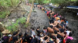 Warga berjalan menyusuri hutan mangrove saat mengikuti tradisi mandi lumpur atau mebuug-buugan di Desa Kedonganan, Denpasar, Bali, Jumat (8/3). Mebuug-buugan diikuti ratusan warga ini digelar di hutan mangrove. (Sonny Tumbelaka/AFP)