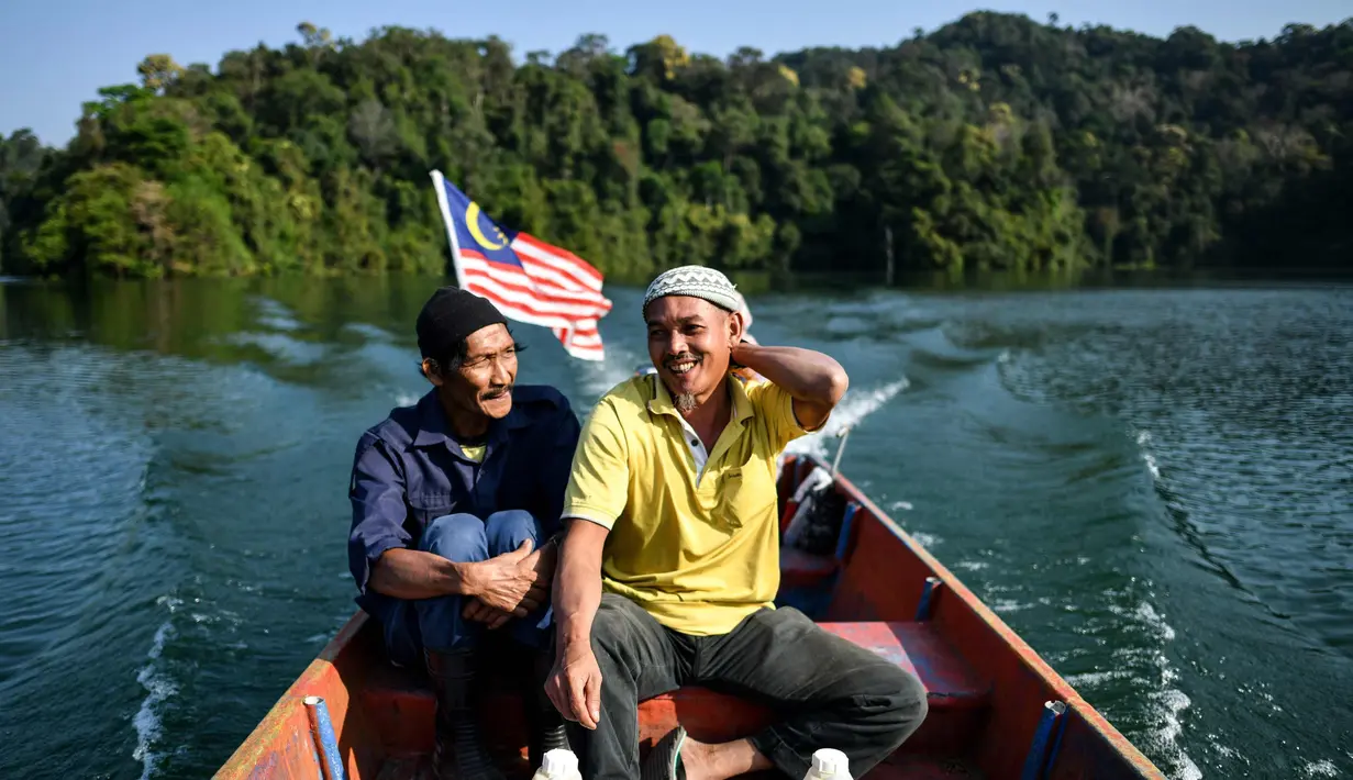 Pemburu madu Malaysia tradisional Zaini Abdul Hamid (kanan) dan Abdul Samad Ahmad menaiki perahu usai mengumpulkan madu dari sarang lebah di hutan Ulu Muda di Sik, timur laut negara bagian Malaysia, Kedah (12/3). (AFP Photo/Manan Vatsyayana)