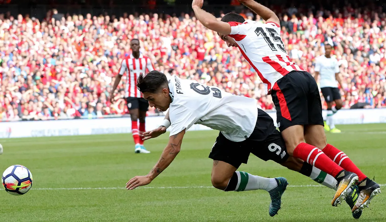 Striker Liverpool, Roberto Firmino, dijatuhkan bek Athletic Bilbao, Inigo Lekue, pada laga persahabatan di Stadion Aviva, Dublin, Sabtu (5/8/2017). Liverpool menang 3-1 atas Athletic Bilbao. (AFP/Paul Faith)