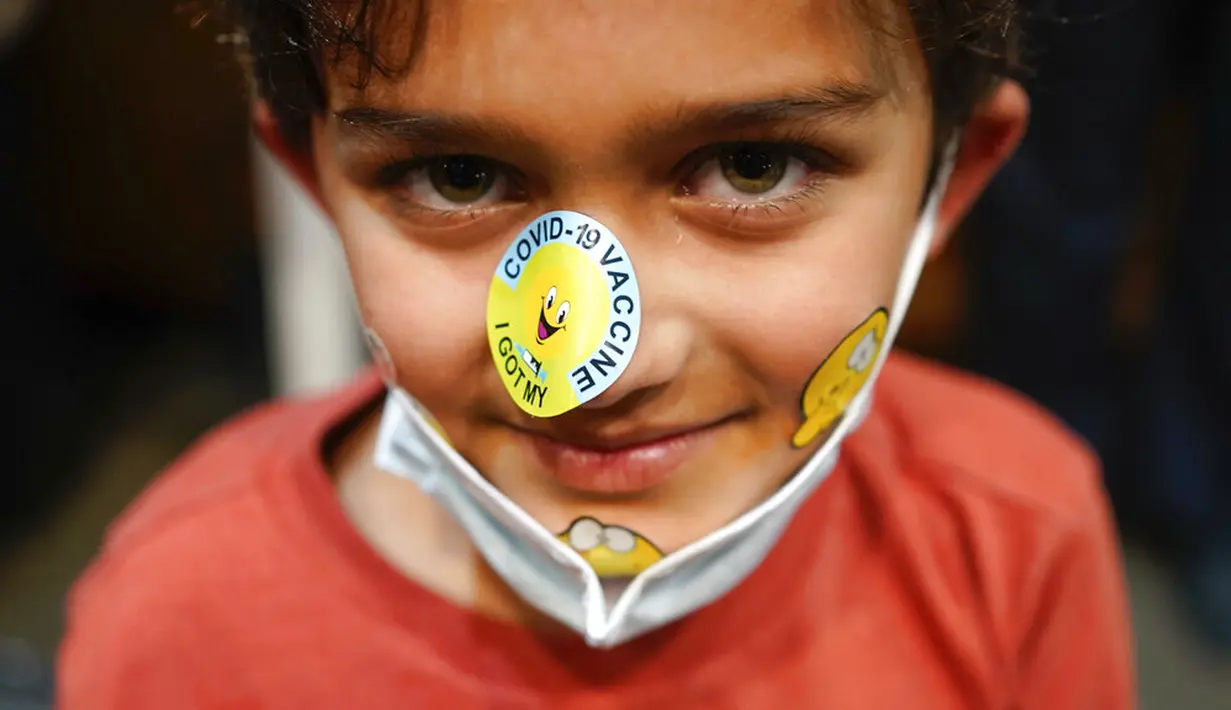 Paul Srinivasan (7) tersenyum saat menunjukkan stiker pada wajahnya usai menerima vaksinasi COVID-19 di Englewood Health, Englewood, New Jersey, Amerika Serikat, 8 November 2021. AS gelar vaksinasi COVID-19 untuk anak-anak berusia 5-11 tahun. (AP Photo/Seth Wenig)