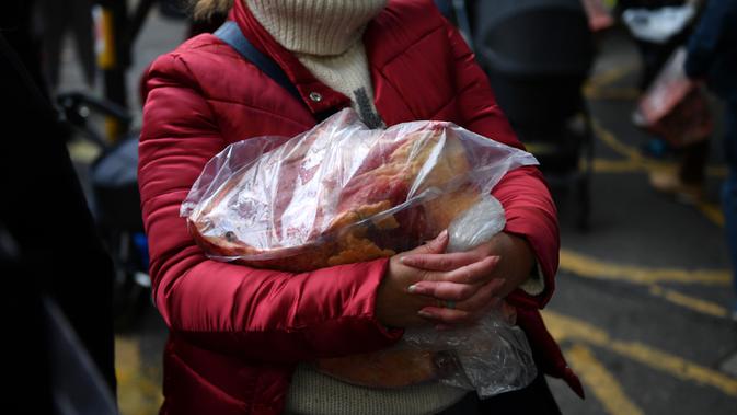Seorang pelanggan membawa pulang potongan daging selama lelang tahunan menyambut malam Natal di Smithfield Market, London, Selasa (24/12/2019). Operasi pasar ini menjadi sarana menghabiskan persediaan para pemilik toko jelang tahun baru. (DANIEL LEAL-OLIVAS / AFP)