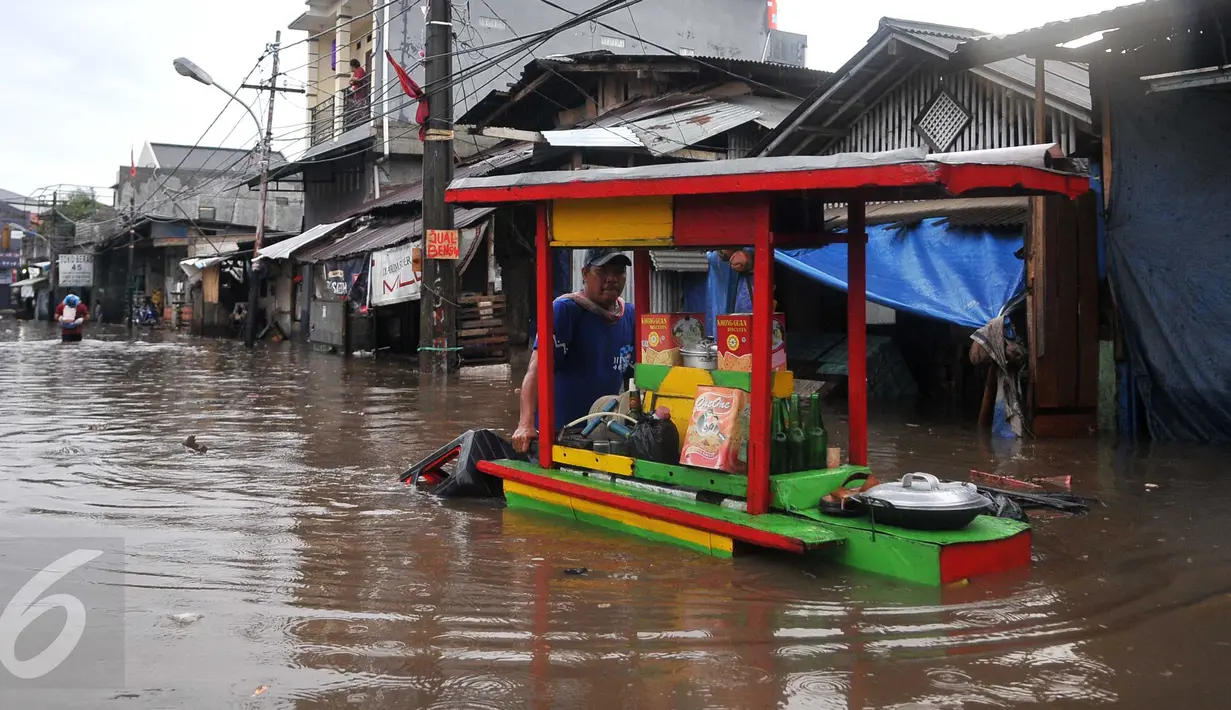 Pedagang Ketoprak menerobos banjir di kawasan Pasar Buncit, Jakarta Selatan, Selasa (9/2/2016). Banjir menggenangi kawasan tersebut hingga setinggi 100 cm akibat luapan Kali Kemang. (Liputan6.com/Gempur M Surya)