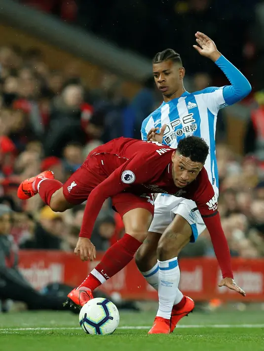 Gelandang Liverpool, Alex Oxlade-Chamberlain berebut bola dengan pemain Huddersfield Town, Juninho Bacuna dalam laga lanjutan Premier League 2018-19 pekan ke-36 di Anfield, Jumat (26/4). Bermain di kandang sendiri, Liverpool menang dengan skor telak 5-0.  (REUTERS/Andrew Yates)