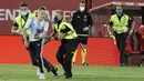 Petugas keamanan menangkap seorang penyusup yang masuk ke lapangan saat pertandingan La Liga antara Mallorca dengan FC Barcelona di Son Moix Stadium, Palma de Mallorca, Spanyol, Sabtu (13/6/2020). Dalam pertandingan tersebut Barcelona mengalahkan Mallorca dengan skor 4-0. (AP Photo/Francisco Ubilla)