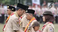 Presiden Joko Widodo memberi tanda kehormatan kepada seorang anak saat perayaan hari jadi Pramuka yang ke-57 di Lapangan Gajah Mada, Wiladatika, Cibubur, Jakarta, Selasa (14/8). (Liputan6.com/Faizal Fanani)