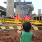 Seorang anak melihat kondisi tiang girder Tol Bekasi-Cawang-Kampung Melayu (Becakayu) yang ambruk di Kebon Nanas, Jakarta Timur, Selasa (20/2). Peristiwa terjadi saat para pekerja melakukan pengecoran pada penyangga tiang. (Liputan6.com/Arya Manggala)