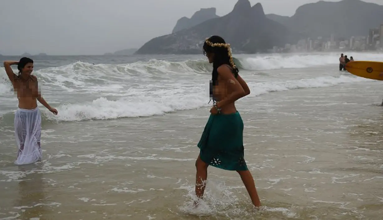 Dua wanita anggota gerakan topless mengumbar payudaranya saat melakukan ritual untuk Lemanja di Pantai Arpoador, Rio de Janeiro, Brasil, Senin (2/2/2015). (AFP Photo/Yasuyoshi Chiba)