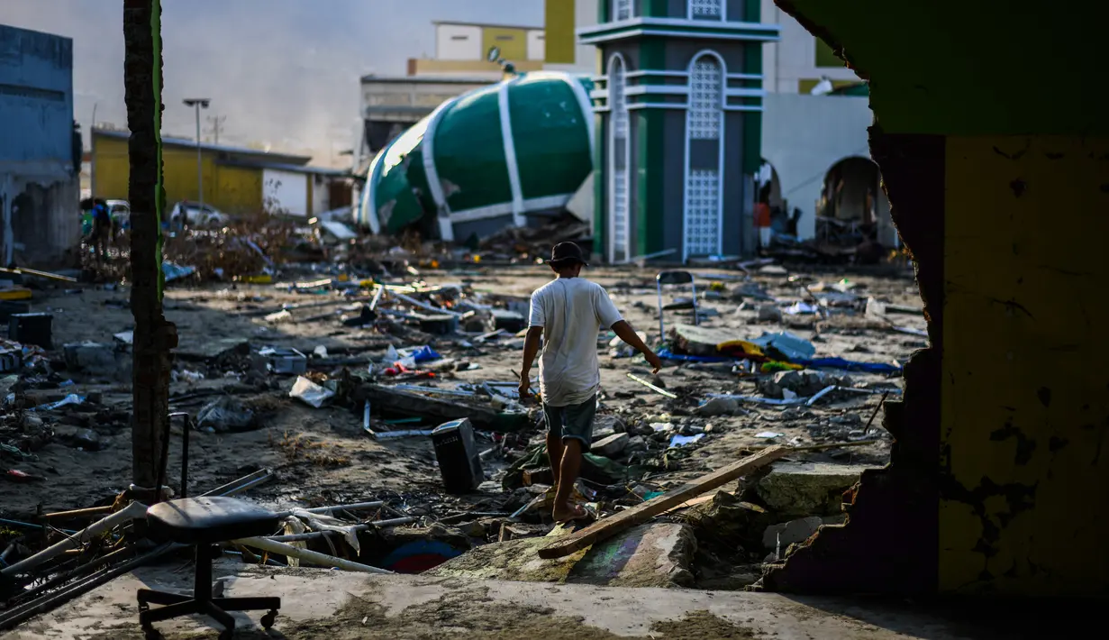 Warga melewati puing-puing dekat Masjid Raya Baiturrahman yang runtuh setelah gempa bumi dan tsunami di Palu, Sulawesi Tengah, Rabu (3/10). Meski kubah dan beberapa dinding masjid runtuh, namun menaranya masih kokoh berdiri. (AFP PHOTO / JEWEL SAMAD)