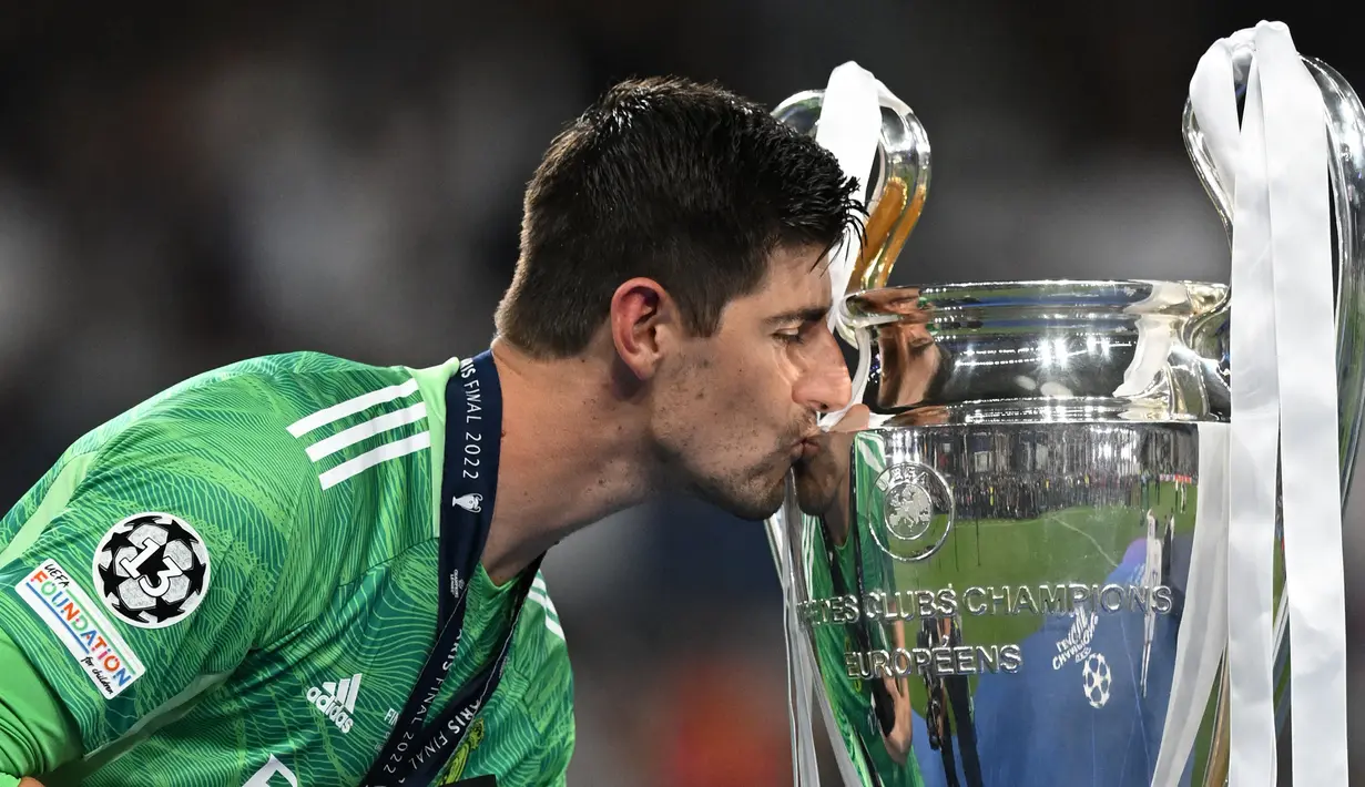 Kiper Real Madrid, Thibaut Courtois mencium trofi Liga Champions saat upacara penyerahan medali setelah Real Madrid keluar sebagai pemenang di laga final melawan Liverpool yang berlangsung di Stade de France, Saint Denis, Sabtu, 28 Mei 2022 waktu setempat. (AFP/Paul Ellis)