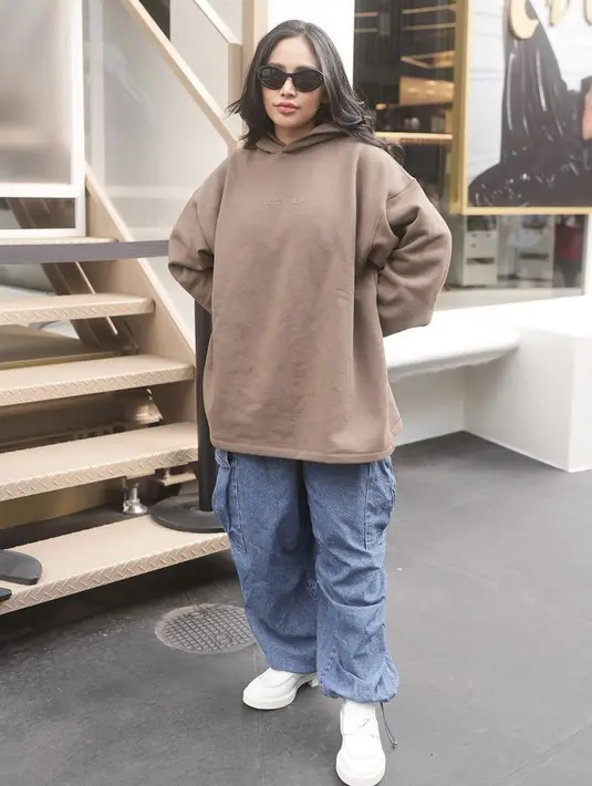 Tak hanya tampil terbuka, ia tampil tertutup mengenakan hoodie oversize coklat dengan celana cargo denim.  (@rachelvennya)