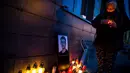 Seorang wanita menyalakan lilin di dekat foto Jan Kuciak di Bratislava (26/2). Pembunuhan itu terjadi di tengah pembuatan laporan investigatif Kuciak soal kasus dugaan kecurangan pajak yang melibatkan pengusaha. (AFP Photo/Vladimir Simicek)