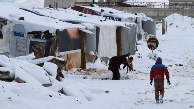 Pengungsi Suriah berjalan di salju sebuah kemah darurat di pinggiran Baalbek, Lebanon (AFP Photo)