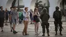 Wisatawan berbincang dengan tentara saat mereka berpatroli di lingkungan Lapa di Rio de Janeiro, Brasil, (30/7). Ribuan tentara mulai berpatroli di Rio de Janeiro di tengah lonjakan kekerasan di kota terbesar kedua di Brasil. (AP Photo / Leo Correa)