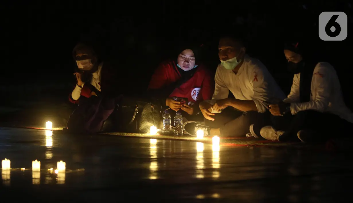 Sejumlah relawan menyalakan lampu pada malam renungan Hari AIDS Sedunia di Tanah Abang, Jakarta, Rabu (1/12/2021). Acara ini mengampanyekan kepada masyarakat untuk mewaspadai penularan virus HIV/AIDS dan lebih berempati pada penderitanya. (Liputan6.com/Herman Zakharia)