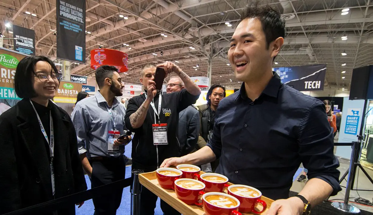 Pengunjung melihat latte kreasi peserta Anskar Shin (kanan) dalam Kompetisi Seni Latte yang merupakan bagian dari Pameran Restoran Kanada 2020, Toronto, Kanada (3/3/2020). Total delapan peserta dari seluruh wilayah di Kanada ambil bagian dalam ajang nasional ini pada Selasa (3/3). (Xinhua/Zou Zheng)