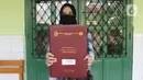 Wali murid menunjukkan laporan hasil belajar (rapor) kenaikan kelas di SD Negeri Menteng 01 Jakarta, Kamis (25/6/2020). Pembagian dilaksanakan mengikuti protokol kesehatan COVID-19 serta membagikan rapor secara bertahap dari 24-26 Juni 2020. (Liputan6.com/Herman Zakharia)