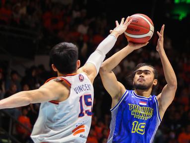 Pebasket Prawira Bandung, M. Reza Fahdani Guntara (kanan) berusaha menembak bola ke arah ring Pelita Jaya pada laga gim pertama final IBL 2023 di Hall Senayan, Jakarta, Kamis (20/07/2023). Laga dimenangkan oleh Prawira Bandung dengan skor 74-65. (Bola.com/Bagaskara Lazuardi)