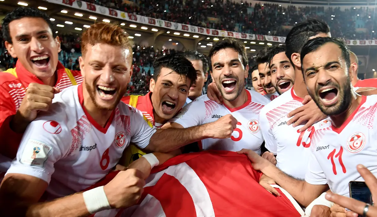 Pemain Timnas Tunisia melakukan selebrasi usai pertandingan melawan Libya dan dinyatakan lolos ke Piala Dunia 2018 di Stadion Olimpiade Rades, Tunisia (11/11). (AFP Photo/Fethi Belaid)
