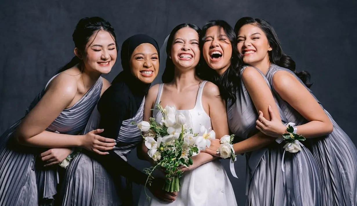 Ketika akad kenakan kebaya, saat resepsi pernikahan para bridesmaid Hanggini kenakan dress off shoulder warna abu-abu. Warna tersebut selaras dengan dress Hanggini yang berwarna putih. Gelang bunga di tangan bridesmaid Hanggini membuat penampilan jadi makin cantik. Foto tersebut memperlihatkan jika Hanggini dan keempat sahabatnya ini sangat dekat hingga dipilih jadi bridesmaid. (Liputan6.com/IG/@animrf)