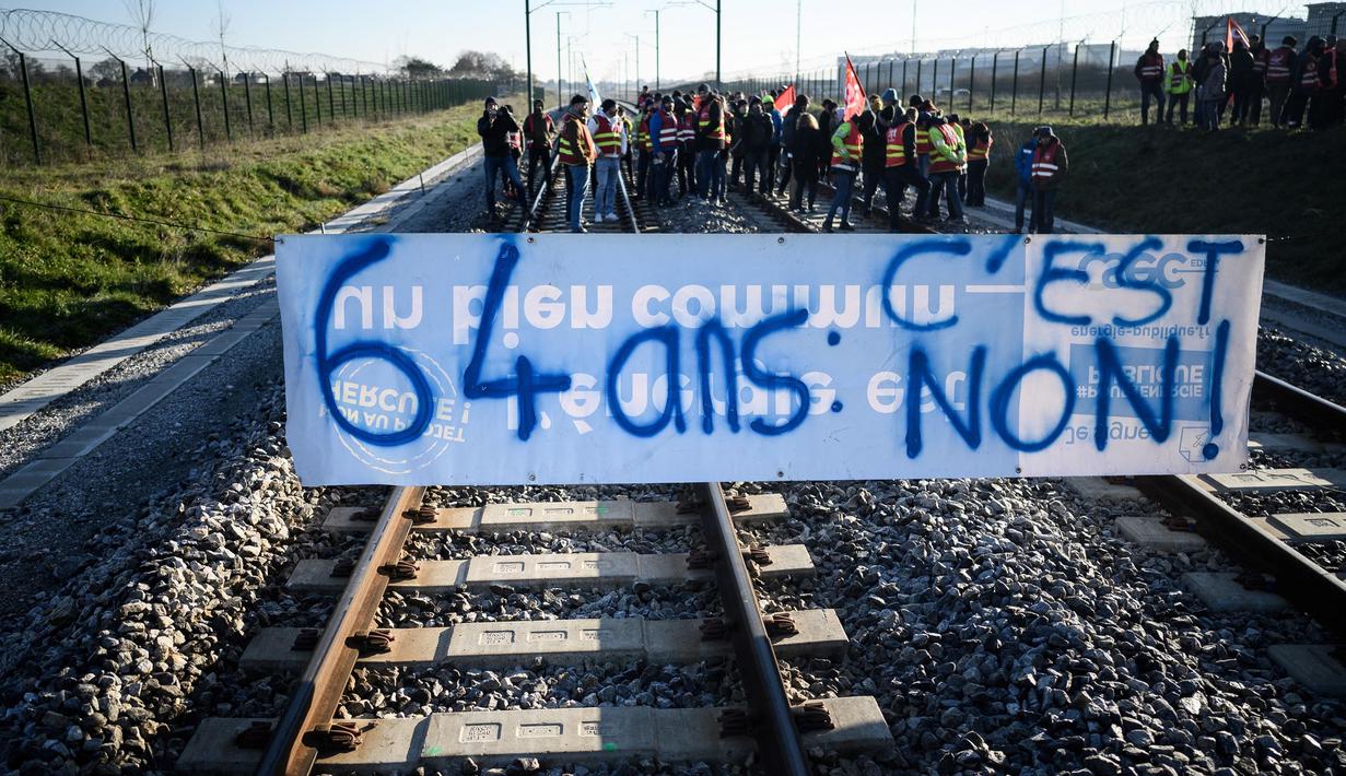 Pengunjuk rasa berdiri di rel kereta api di belakang spanduk bertuliskan "64 tahun, tidak" dalam sebuah aksi yang diserukan oleh serikat pekerja Prancis, Konfederasi Umum Buruh (CGT), untuk memprotes perombakan pensiun di Donges, Prancis Barat, Rabu (8/2/2023). Prancis bersiap menghadapi pemogokan baru dan demonstrasi massal menentang proposal Presiden Prancis untuk mereformasi pensiun Prancis, termasuk menaikkan usia pensiun dari 62 menjadi 64 tahun. (LOIC VENANCE/AFP)