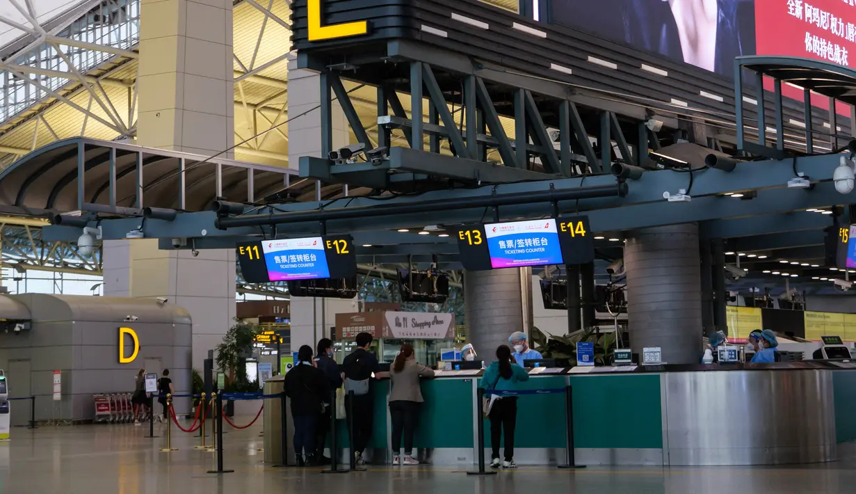 Penumpang berbaris di konter check-in China Eastern di Bandara Internasional Baiyun, Guangzhou, selatan China, Senin (21/3/2022). Pesawat Boeing 737 milik China Eastern Airlines yang membawa yang terdiri dari 123 penumpang dan sembilan awak kabin, jatuh di kawasan lereng gunung. (STR/AFP)