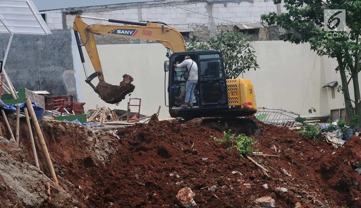 Pekerja dibantu alat berat membersihkan tanah longsor di Kali Jantung, kawasan Perumahan Cluster Azzura, Sukamaju, Depok, Jawa Barat, Kamis (21/2). Turap yang tengah dalam proses pembangunan tersebut ambrol Rabu (20/2/2019). (Liputan6.com/Herman Zakharia)