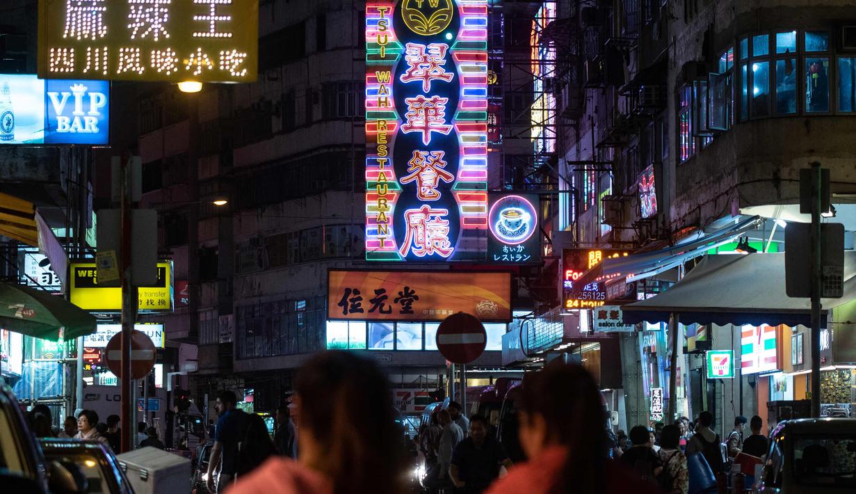 Pejalan kaki berjalan di depan neon sign dari 'Tsui Wah Restaurant' di Hong Kong (16/4). Kota Hong Kong  tidak pernah benar-benar kehilangan kegelapannya berkat cahaya 24 jam dari segudang neon sign. (AFP Photo/Philip Fong)