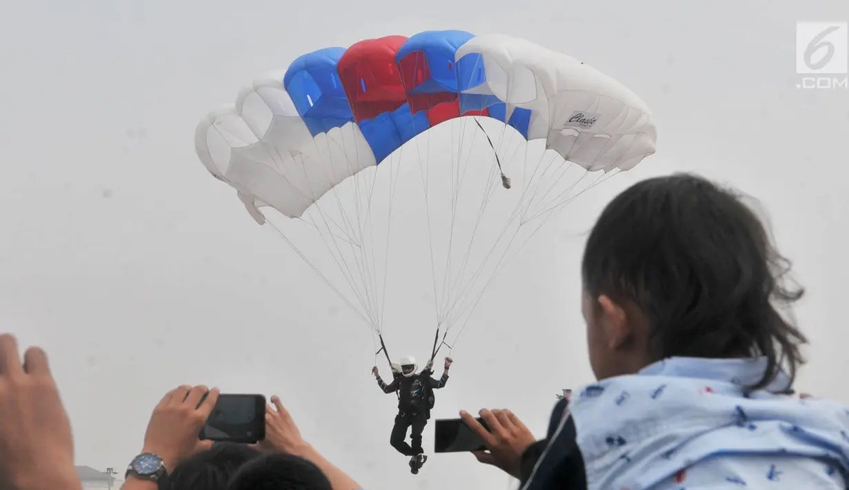 Warga menyaksikan aksi terjun payung saat Festival Damai Millenial Road Safety di Monas, Jakarta, Minggu (23/6/2019). Aksi puluhan penerjun payung TNI-Polri ini menjadi perhatian warga di akhir acara Festival Damai. (merdeka.com/Iqbal Nugroho)