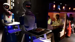 Dua pelayan robot membawa hidangan untuk pelanggan di Chennai, India (20/12). Restoran ini merupakan yang pertama di India yang memiliki pelayan robot dengan server otomatis membawa piring dari dapur ke pelanggan. (AFP Photo/Arun Sankar)