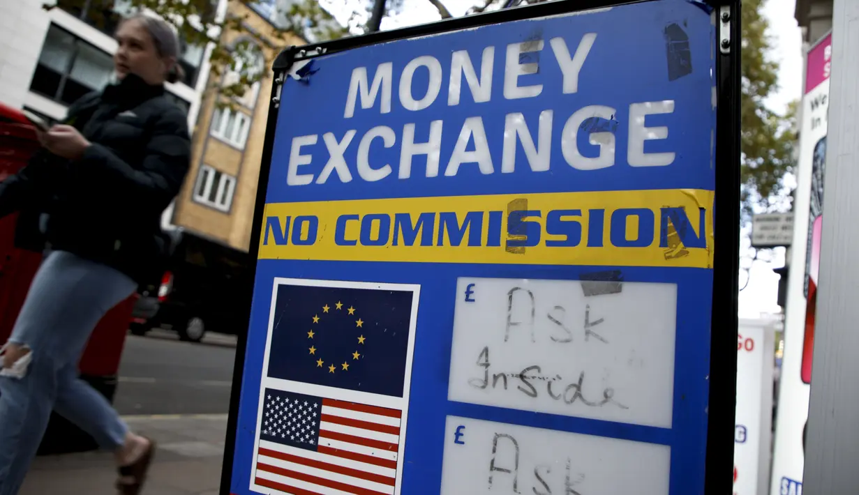 Seorang perempuan berjalan melewati biro penukaran mata uang di London, Senin, 26 September 2022. Jika poundsterling tetap pada level terendah terhadap dolar, maka komoditas impor yang menggunakan nilai dolar termasuk minyak dan gas akan lebih mahal. (AP Photo/David Cliff)