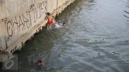 Sejumlah anak bermain dan berenang di anak Kali Ciliwung, Jakarta, Rabu (13/7). Bersihnya kali yang berada di Ibu Kota itu dimanfaatkan anak-anak sekitar untuk berenang sambil mengisi waktu libur sekolah. (Liputan6.com/Immanuel Antonius)