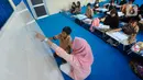 Seorang guru mengajar murid tanpa menggunakan meja dan kursi sekolah, di SDN Bojong Nangka 02, Kabupaten Bogor, Jawa Barat, Kamis (16/2/2023). Sudah lebih dari dua pekan, murid-murid di tiga ruang kelas  menerapkan kegiatan belajar mengajar beralas karpet karena belum tersedianya bangku dan meja. (merdeka.com/Arie Basuki)