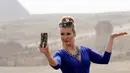 Gaya Kontestan Miss ECO Universe saat berselfie dengan latar belakang segitiga piramida di pinggiran Kairo, Mesir (10/4). Pemenang Miss Eco 2016 akan memenangkan hadiah uang tunai USD 10.000. (REUTERS/Mohamed Abd El Ghany)