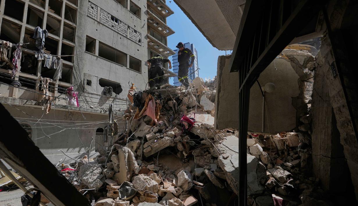 Warga mengatakan sejumlah serangan udara Israel dilakukan tanpa peringatan evakuasi seperti biasanya. Tampak dalam foto, para pekerja pertahanan sipil Lebanon memeriksa puing-puing di lokasi bangunan yang hancur akibat serangan udara Israel sehari sebelumnya di Beirut, Lebanon, Kamis 9 April 2026. (AP Photo/Hussein Malla)