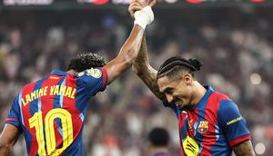 Lamine Yamal (kiri) dan Raphinha (kanan) melakukan selebrasi merayakan sukses meraih gelar Piala Super Spanyol seusai menaklukkan Real Madrid, Senin (12/1/2026) dini hari WIB. (Fadel SENNA / AFP)