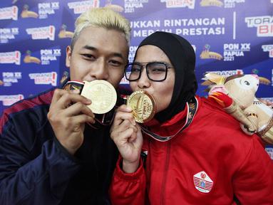 Pasangan suami istri pesilat sama-sama peraih Medali Emas di kelas D  Tanding Putra Putri  dari Jawa Barat Hanifan Yudani Kusumah dan Pipiet Kamelia dari DKI Jakarta berfoto bersama pada PON XX PAPUA  di GOR Toware (12/10) Jayapura. (FOTO: PB PON XX PAPUA/TATAN AGUS RUSTANDI)