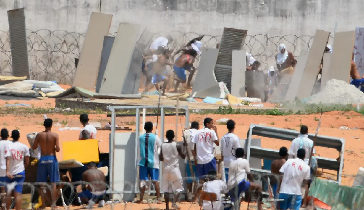 Para tahanan berlari saat polisi membubarkan mereka di penjara Alcacuz, Natal, Rio Grande do Norte, Brasil, (16/1). Kerusuhan dimulai ketika anggota geng narkoba menyerang sektor yang ditempati rival mereka. (AFP Photo/Andressa Anholette)