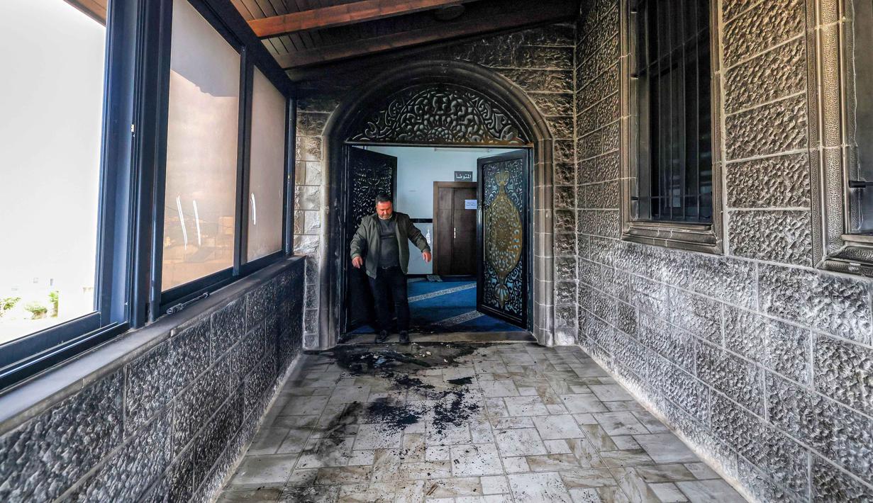Seorang pria memeriksa pintu masuk Masjid Abu Bakr al-Siddiq di desa Tell, sebelah barat Nablus, Tepi Barat yang diduduki, pada 23 Februari 2026. (JAAFAR ASHTIYEH/AFP)