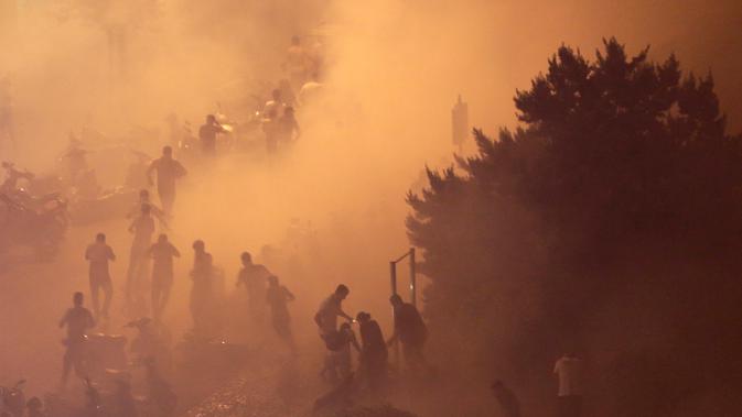 Pengunjuk rasa berlarian saat polisi menembakkan gas air mata untuk membubarkan massa selama protes menentang rencana pengenaan pajak baru di Beirut, Lebanon, Jumat (18/10/2019). Massa marah kepada para politisi yang mereka tuduh korup dan salah urus negara. (AP Photo/Hassan Ammar)