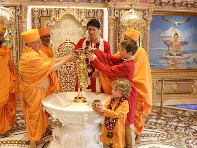 Perdana Menteri Kanada Justin Trudeau bersama dua anaknya mengikuti ritual di Kuil Swaminarayan Akshardham, India (19/2). (AFP Photo/Swaminarayan Akshardham Temple)