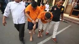 Petugas membawa tersangka beserta barang bukti kasus penipuan dengan ATM di Mapolres Metro Jakarta Barat, Senin (14/8). (Liputan6.com/Immanuel Antonius)