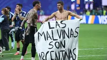 Gelandang Argentina Giovani Lo Celso menunjukkan spanduk bernuansa politik usai semifinal Piala Dunia 2026 melawan Inggris. (AFP/Thomas Coex)