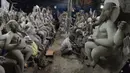Perajin membuat patung Dewa Ganesha di sebuah bengkel di pinggiran Hyderabad, India, Rabu (18/8/2021). ​Patung ramah lingkungan yang dibuat jelang perayaan Ganesh Chaturthi tersebut dibuat dari lumpur, serat rami, dan bambu untuk mengurangi polusi air. (NOAH SEELAM/AFP)