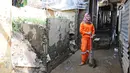 Petugas PPSU Kelurahan Kampung Melayu Siti Hajar berpose saat membersihkan sisa lumpur akibat banjir yang melanda Kebon Pala, Jakarta, Kamis (25/4). Siti Hajar (19) merupakan lulusan SMK yang baru 4 bulan bekerja menjadi pasukan oranye. (Liputan6.com/Herman Zakharia)