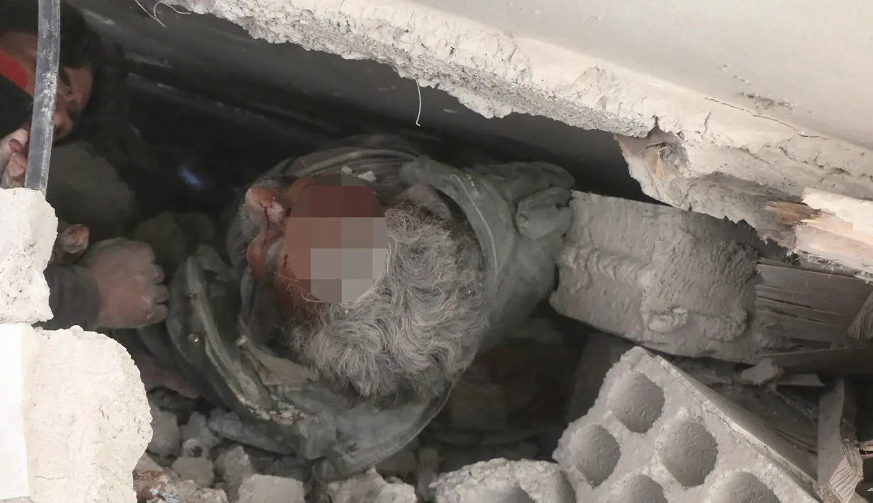 Pria terjebak di bawah reruntuhan bangunan usai serangan udara pasukan pemerintah di Ghouta Timur, Damaskus, Suriah, Selasa (20/2). Pasukan pemerintah diduga bersiap melakukan serangan darat ke lokasi tersebut. (Syrian Civil Defense White Helmets via AP)