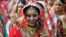Seorang perempuan tersenyum saat mengikuti nikah massal di Surat, India, Minggu (23/12). Nikah massal ini juga diikuti oleh enam pasangan pengantin Muslim dan tiga pasangan Kristen. (AP/Ajit Solanki)