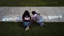 Dua gadis menulis kata-kata penyemangat di jalan setapak di alun-alun kota di mana sebuah peringatan didirikan untuk para korban yang tewas dalam penembakan di sekolah dasar awal pekan ini di Uvalde, Texas, Amerika Serikat, 28 Mei 2022. (AP Photo/Jae C.Hong)