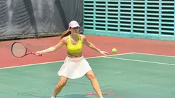 Aksi Pevita Pearce saat berusaha mengembalikan bola tenis dari lawannya dengan mengayunkan raket berwarna merah di tangan kanannya. (Instagram/pevpearce)
