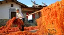 Seorang warga menjemur kulit buah kesemek di halaman rumahnya di Desa Anxi, Fujian, selatan China, 13 Desember 2016. Sejumlah warga memanfaatkan atap rumah mereka untuk mengeringkan kesemek yang akan dijadikan manisan. (REUTERS/Stringer)