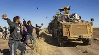 Sejumlah warga Kurdi melemparkan batu ke kendaraan militer Turki di dekat kota Al-Muabbadah, bagian timur laut Hassakah, Suriah (8/11/2019). Aksi dilakukan memprotes  terhadap serangan militer yang dilancarkan Turki. (AFP/Delil Souleiman)